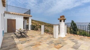 A patio with a table and chairs, a white door, and a view of the landscape. - Casa Rural Museo del Trovo y Aguardiente Murtas by Ruralidays (Granada)