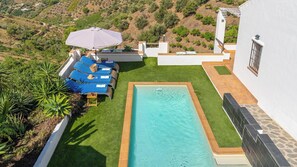 A swimming pool with a surrounding deck, lounge chairs, and an umbrella. - Villa Hop House Frigiliana by Ruralidays (Málaga)