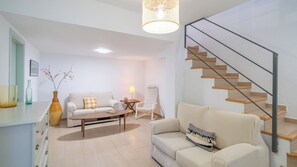 A modern living room with a sofa, a coffee table, a lamp, a vase with branches, and a staircase. - Villa Hop House Frigiliana by Ruralidays (Málaga)