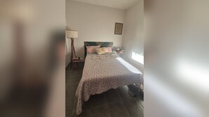 A bedroom with a bed, a bedside table, a lamp, and a window. - Country house on the reservoir with beach, kayaking, fishing and waterfall. (Juquitiba)