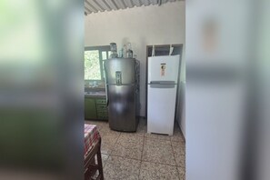 A kitchen with a stainless steel refrigerator, a white refrigerator, and a table with a checkered tablecloth. - Country house on the reservoir with beach, kayaking, fishing and waterfall. (Juquitiba)