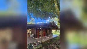 A wooden cabin with a covered porch, a bench, and a small table. - Country house on the reservoir with beach, kayaking, fishing and waterfall. (Juquitiba)