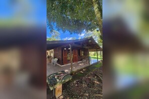 Eine Holzhütte mit verdeckter Veranda, einer Bank und einem kleinen Tisch.