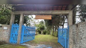 A gated entrance with a sign reading 'Vale da Luz' and a blue fence. - Country house on the reservoir with beach, kayaking, fishing and waterfall. (Juquitiba)