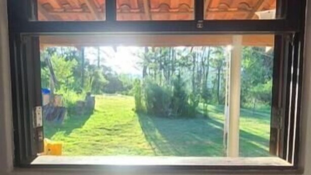A window with a view of a garden and a wooden ceiling. - Country house on the reservoir with beach, kayaking, fishing and waterfall. (Juquitiba)