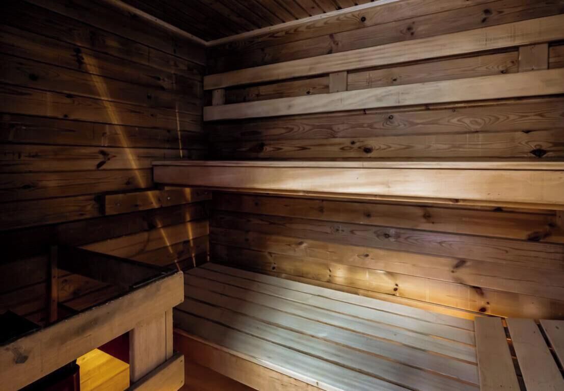 L’intérieur d’un chalet en bois, avec un plafond en pente et un banc le long du mur.
