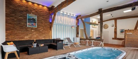 A spa area with a hot tub, lounge chairs, and a wooden wall with a poster.