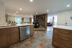 A modern kitchen with a stone wall, built-in appliances, and a dining area with a view. - 8-Acre Retreat with Trails, 7 Min to Killington (Plymouth)