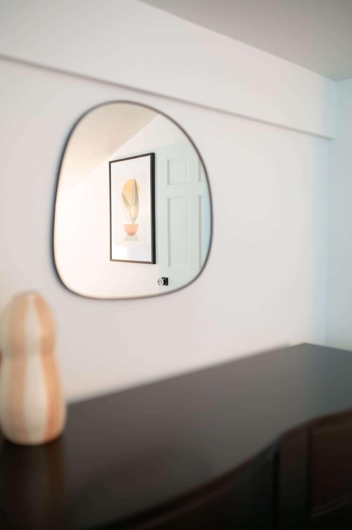 A wall-mounted mirror with a framed picture and a door.