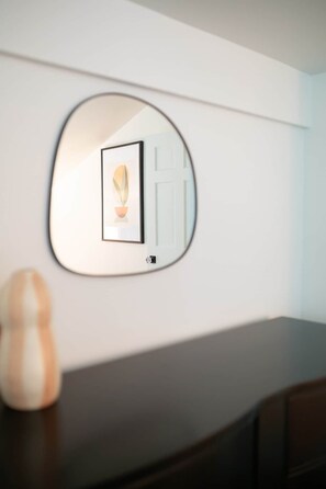 En spegel som hänger på väggen, med en inramad bild och en dörr.