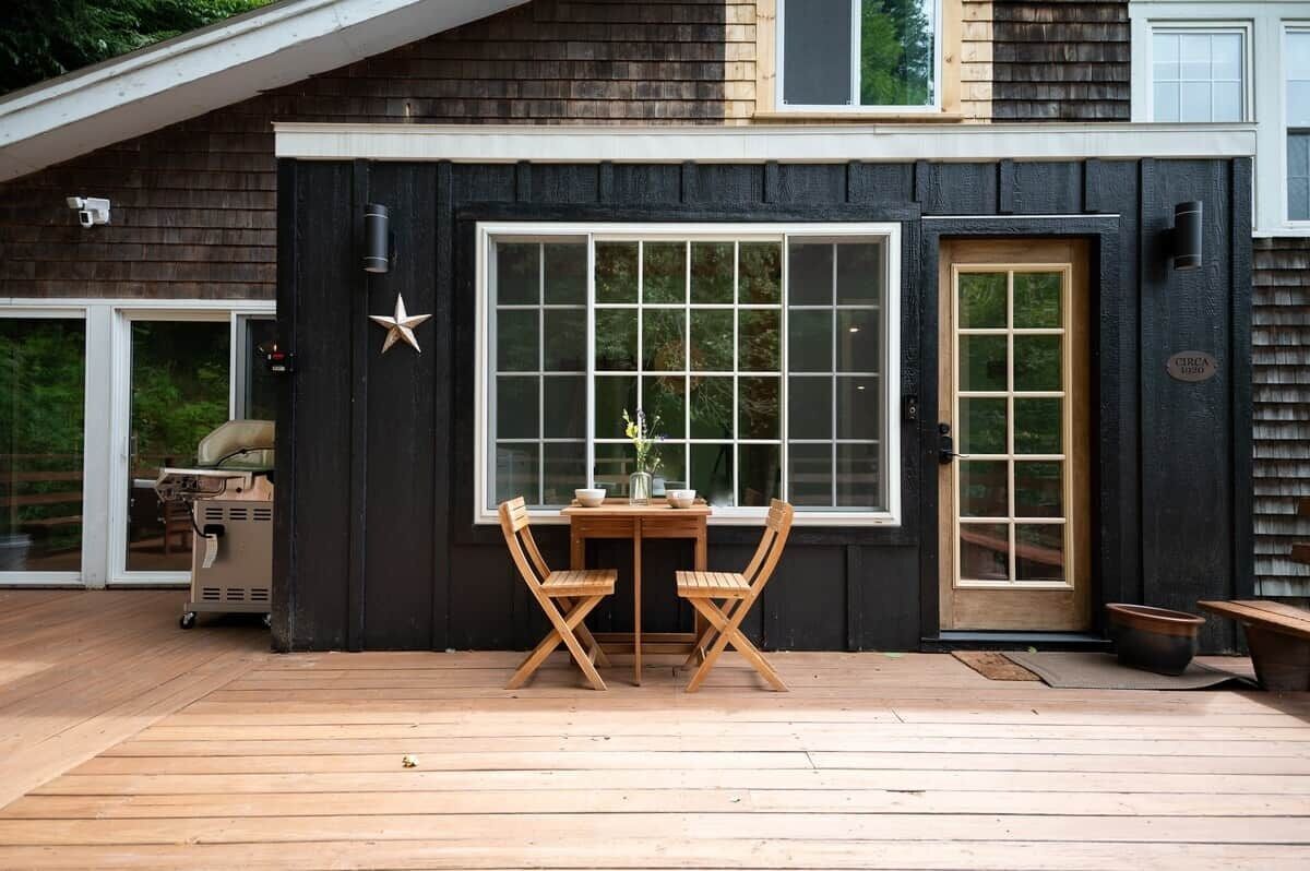 A deck with a table and chairs, a grill, and a large window with a star decoration.