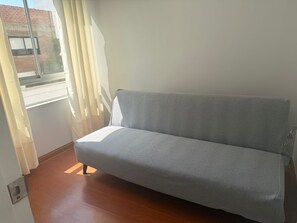 A room with a grey sofa, a window with curtains, and a wooden floor. - Well-Located Apt Near Airport (San Miguel)