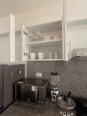 Eine kleine Küchenzeile mit Mikrowelle, Mixer und kleinem Kühlschrank.