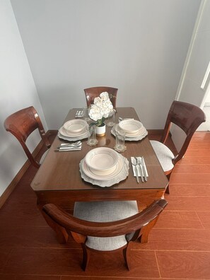 A dining table set with plates, glasses, and cutlery, surrounded by wooden chairs with cushioned seats. - Well-Located Apt Near Airport (San Miguel)