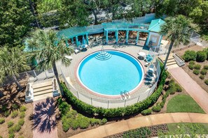 Uma piscina circular com um deck ao redor, área de estar coberta e um perímetro cercado.