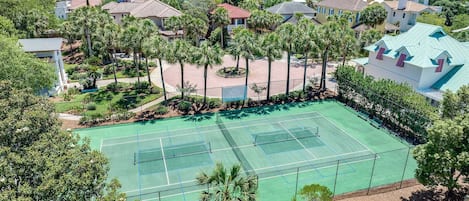 Un court de tennis entouré d’immeubles résidentiels et de palmiers.