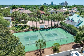 Ein Tennisplatz, umgeben von Wohnhäusern und Palmen.