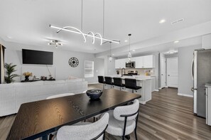 A modern kitchen with white cabinets, a microwave, and a refrigerator.