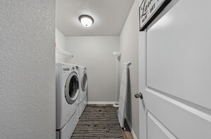 A laundry room with a washing machine, dryer, and a door with a sign above it. - Colorado Springs Family Escape (Colorado Springs)