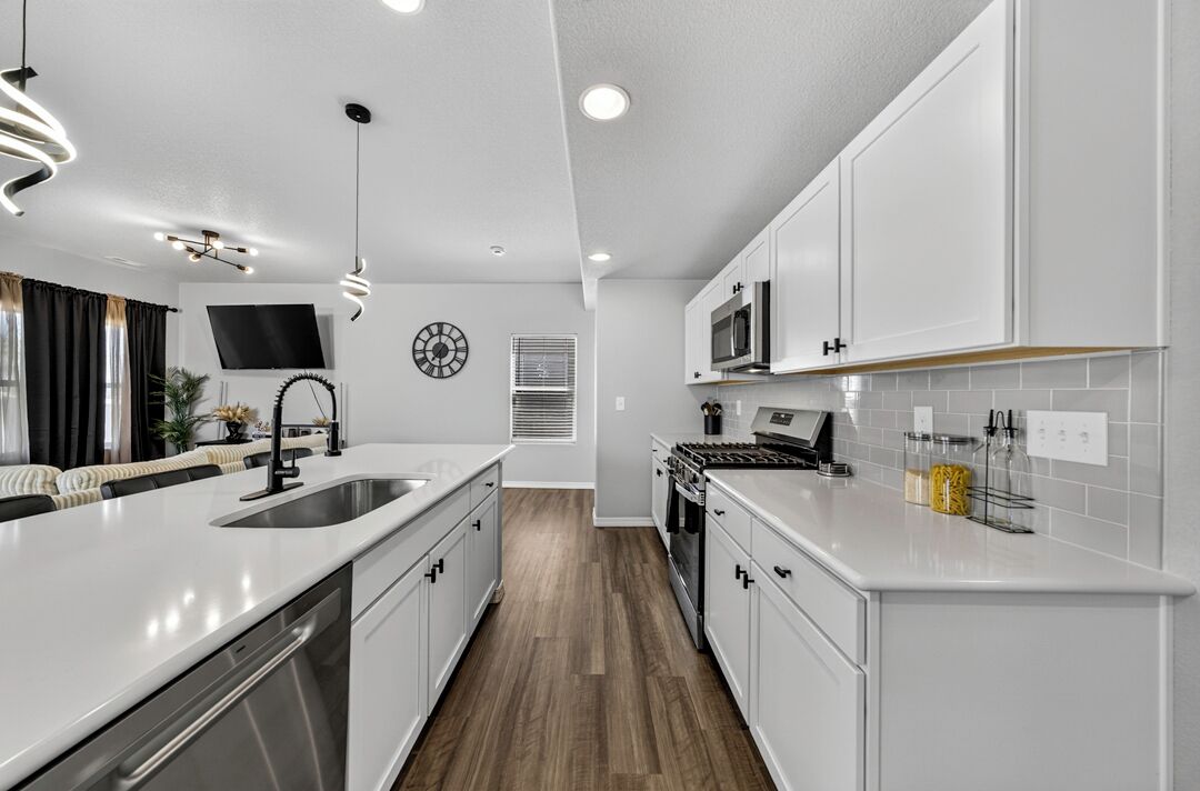 A modern kitchen with white cabinetry, stainless steel appliances, and a central island.