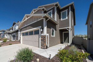 A two-story residential house with a garage, stone foundation, and a well-maintained front yard with landscaping. - Colorado Springs Family Escape (Colorado Springs)
