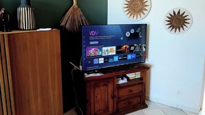 Ein Flachbildfernseher auf einem Holzständer, darüber ein an der Wand befestigtes dekoratives Sonnendesign.
