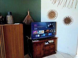 Ein Flachbildfernseher auf einem Holzständer, darüber ein an der Wand befestigtes dekoratives Sonnendesign.