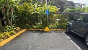 A parking area with a yellow curb, a blue handicap parking sign, and a vehicle parked to the right.