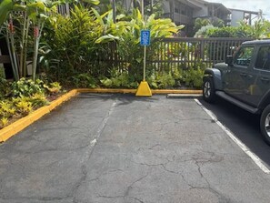 A parking area with a yellow curb, a blue handicap parking sign, and a vehicle parked to the right.