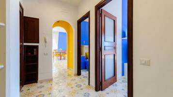 Un pasillo con suelo de baldosas, armarios de madera y una puerta que da a una habitación con pared azul.