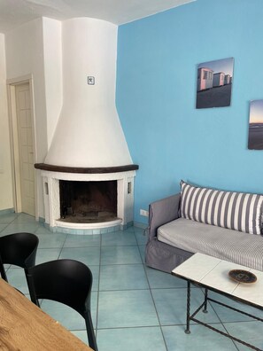 Ein Wohnzimmer mit Kamin, einer Couch und einem Esstisch.