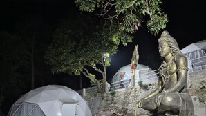 A large outdoor statue of a deity, a tented structure, and a stone wall.