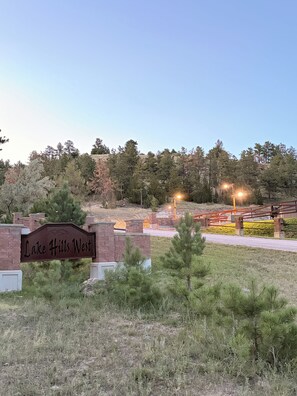 A sign for Lake Hills West with a brick wall and a grassy area in front.