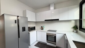 A modern kitchen with white cabinetry, a built-in oven, and a microwave.