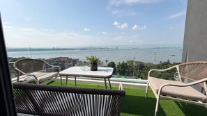Ein Balkon mit Korbmöbeln, einem kleinen Tisch und einem Blumentopf.