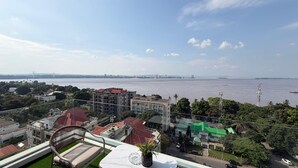 Un edificio alto con vista a un cuerpo de agua y el horizonte de la ciudad a lo lejos.