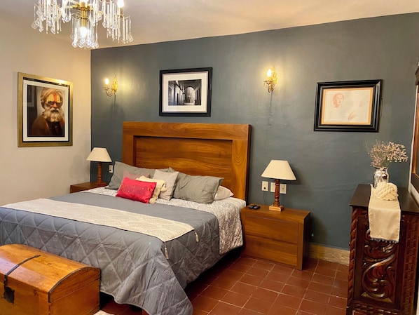 A bedroom with a large bed, two bedside tables, a wooden headboard, and a bench.