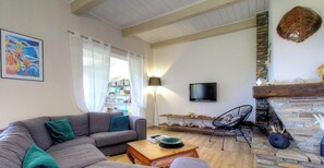Ein Wohnzimmer mit einer Couch, einem Couchtisch, einem Fernseher, einem Bücherregal und einem Kamin.
