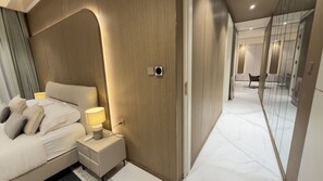 A modern hotel room with a bed, bedside table, lamp, and a mirror.
