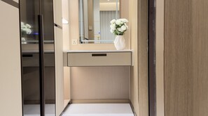 A modern bathroom with a mirror, a vanity, and a vase of flowers.