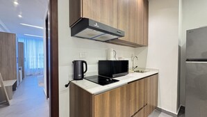 A modern kitchen with a microwave, kettle, and stainless steel refrigerator.