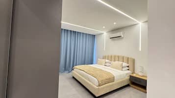 A modern bedroom with a large bed, bedside tables, and an air conditioning unit.