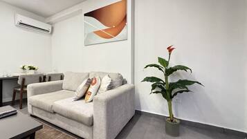 Un salon moderne avec un canapé gris, une plante en pot et une peinture abstraite contemporaine accrochée au mur.