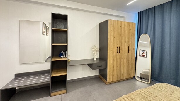 A modern bedroom with a built-in wardrobe, a bedside table, a mirror, and a bed.