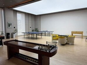 A spacious room with a foosball table, a ping pong table, and a seating area with yellow chairs. - Grand Résidence, 2 Bedrooms Stylish Apartment  Kinshasa (Gombe) – Galerie Lafontaine (Kinshasa)