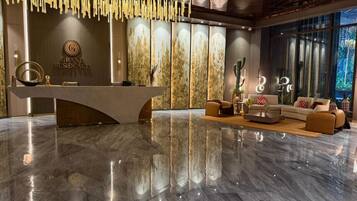 A modern reception area with a marble floor, a reception desk, and a seating area with sofas and a coffee table.