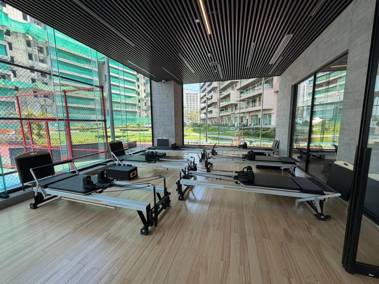 A gym with rowing machines, large windows, and a view of buildings.