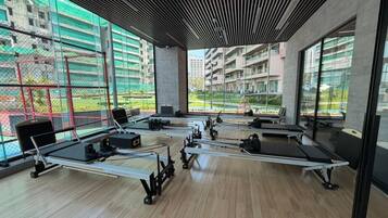 A gym with rowing machines, large windows, and a view of buildings.