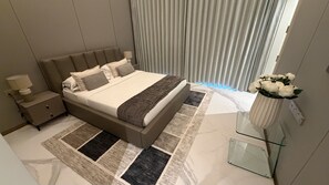 Ein modernes Schlafzimmer mit einem großen Bett, einem Nachttisch, einem Glastisch und einem Blumenstrauß.
