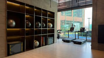 A modern gym with treadmills, a large window, and a wall with exercise equipment.